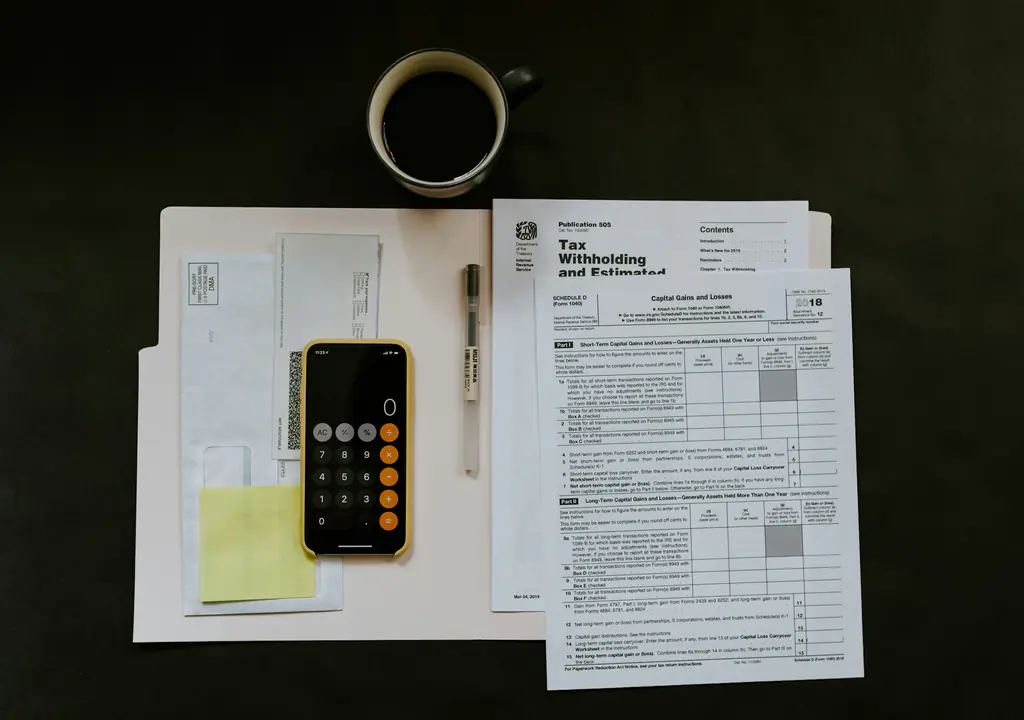 Printed rental paperwork, a calculator and a coffee on a dark desk